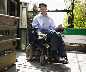 Image of man using a wheelchair disembarking from a subway car.